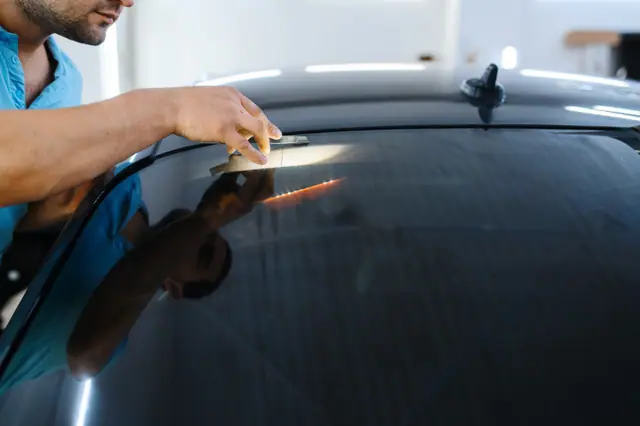 Denton window tint specialist hand-applying film to a car window